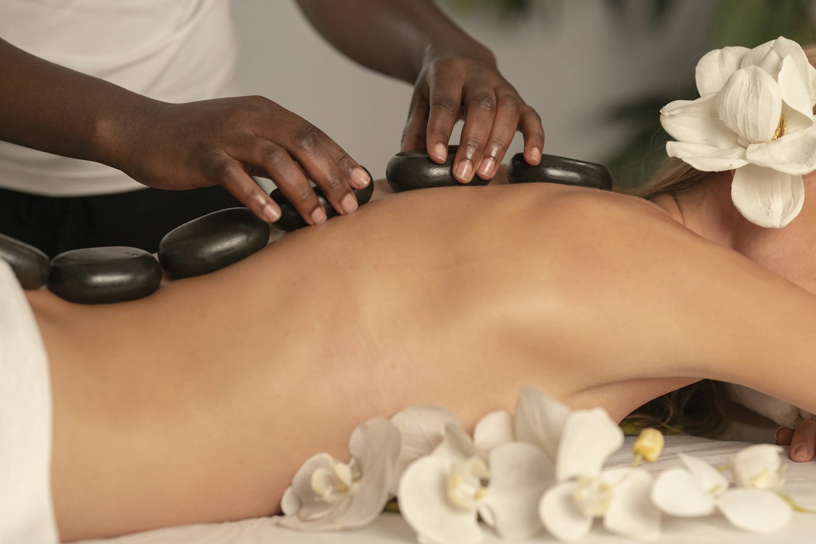 Warm stones and orchids laid across a guest's back during the Renewal SPA Ritual